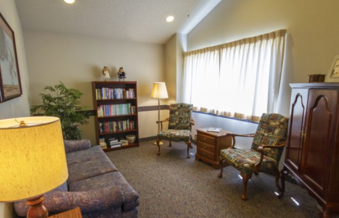 Cozy living room with a bookshelf, sofa, and two chairs by a window.