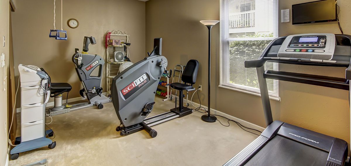 A well-lit home gym with exercise equipment and a stationary bike.