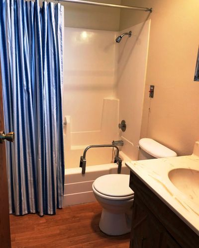 A small bathroom with a blue shower curtain, toilet, sink, and bathtub.