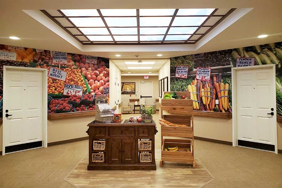 A reception area with vibrant fruit and vegetable murals on the walls, featuring a wooden desk and display stands.