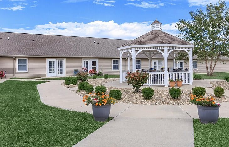 A peaceful garden setting featuring a white gazebo surrounded by well-kept plants and a winding pathway.