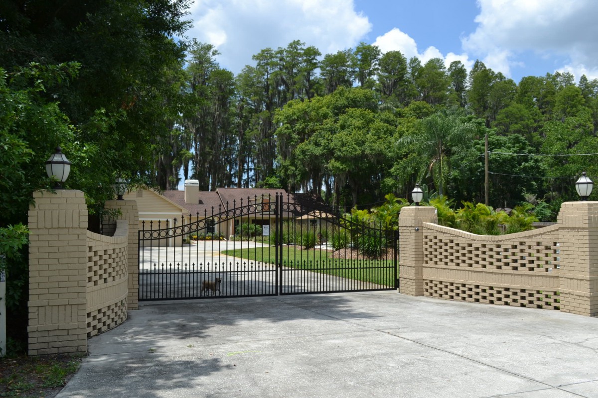 A gated driveway leading to a house surrounded by trees.