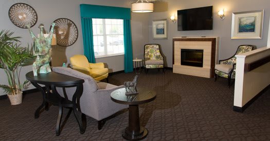 A cozy living room with a sofa, chairs, a fireplace, and a television.