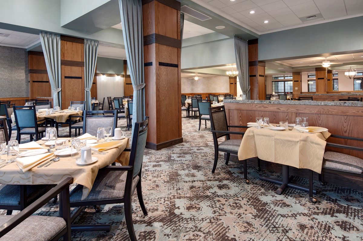 An elegant restaurant dining area with neatly arranged tables and chairs, featuring a warm and inviting interior design.
