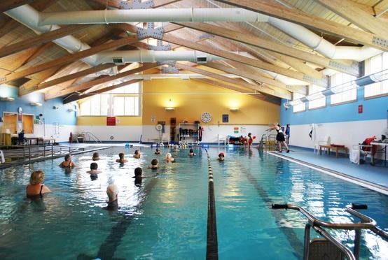 An indoor swimming pool with people engaging in various aquatic activities.