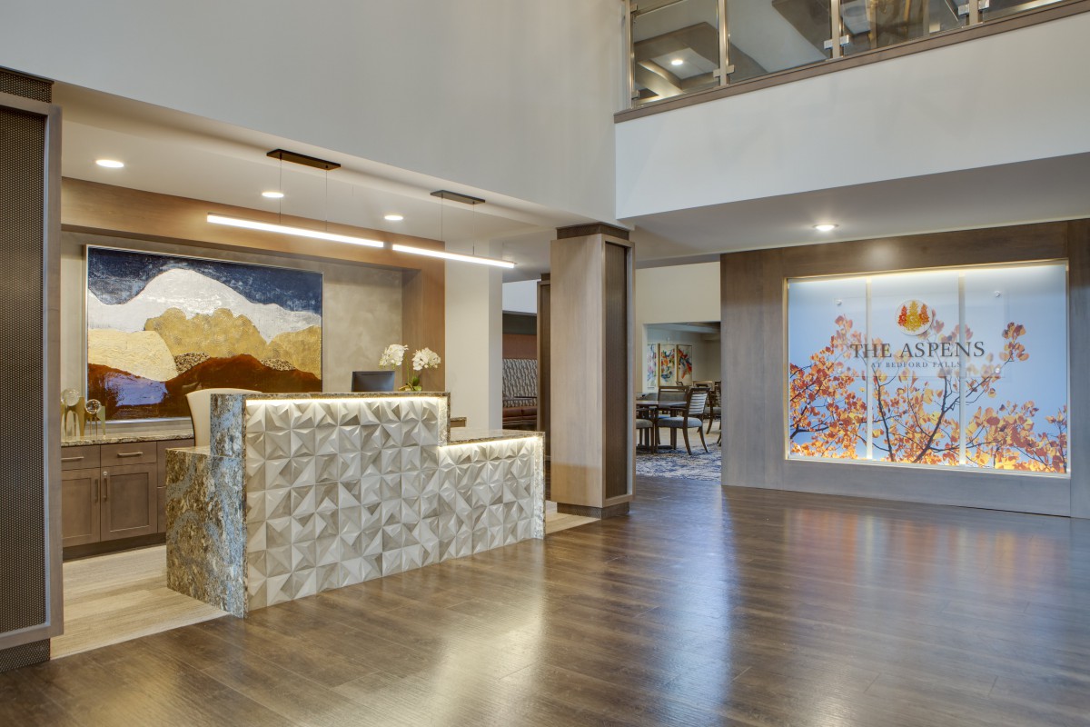 A modern lobby with a stylish reception desk, artwork, and wood flooring.