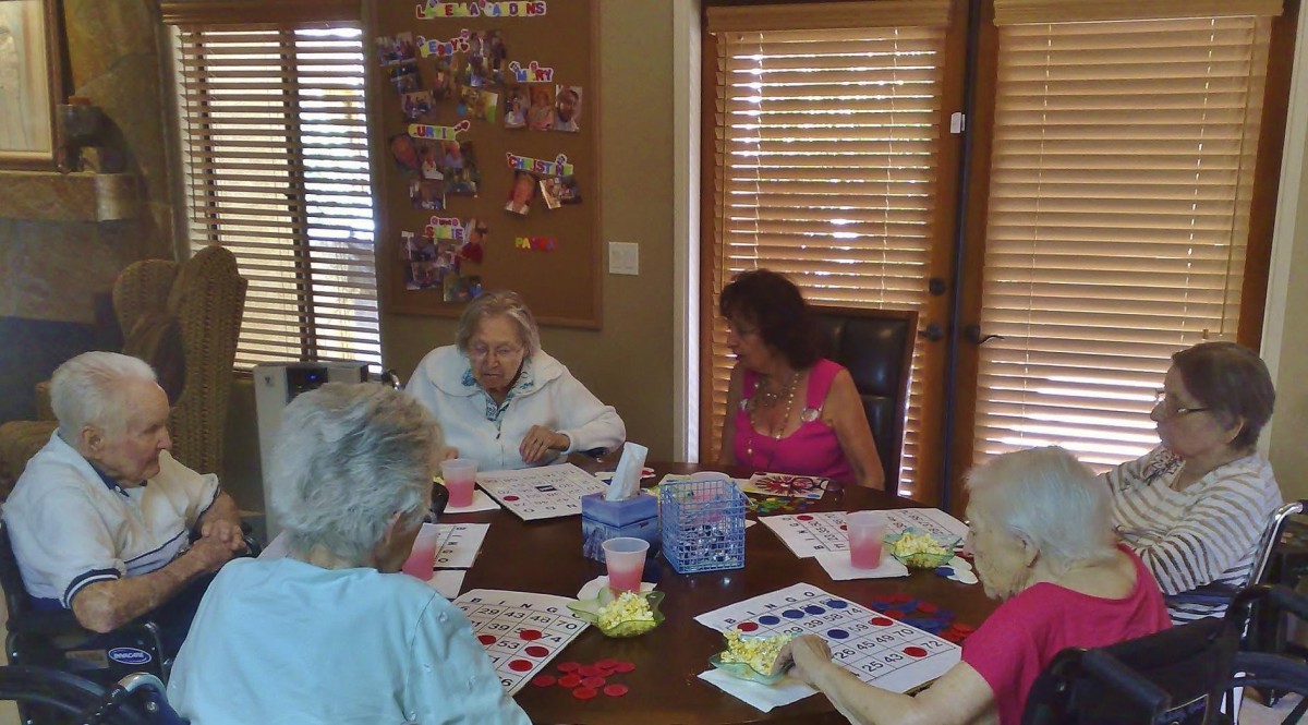 A group of senior citizens engaged in an arts and crafts activity at a table indoors.