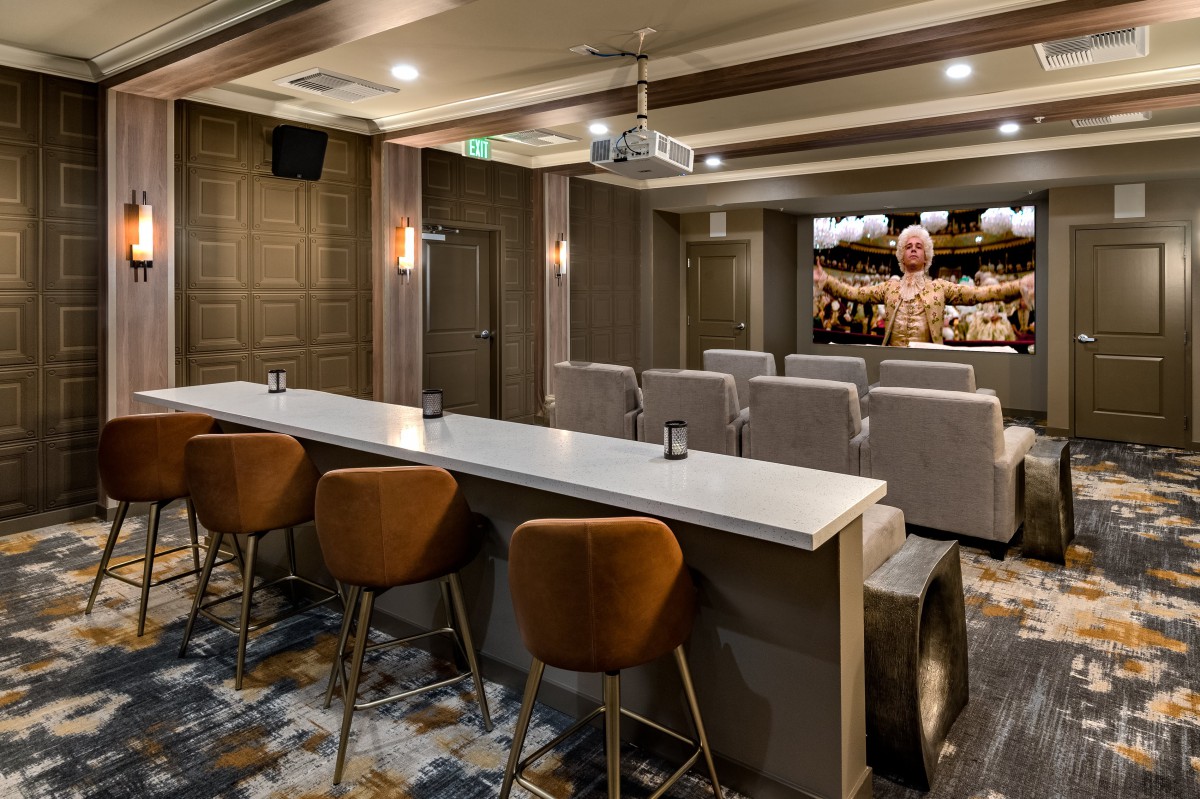 A modern home theater room featuring comfortable seating, a bar area, and a projector for an enhanced viewing experience.