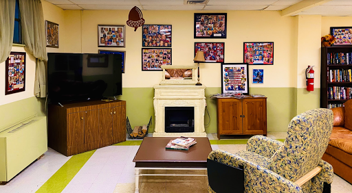 A cozy and welcoming living room space featuring a vintage fireplace, comfortable seating, and a variety of framed photographs on the walls.