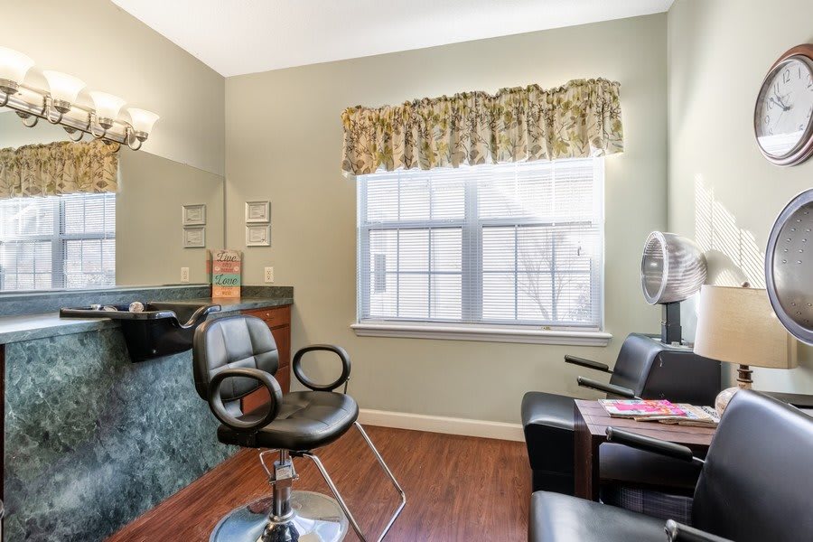 A cozy hair salon interior with a styling chair, mirror, and window letting in daylight.