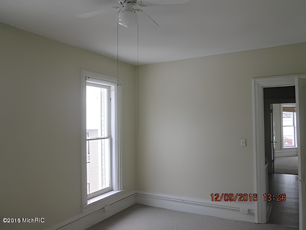 A minimalist empty room with a window and ceiling fan.