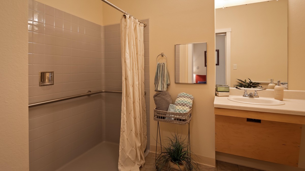 A bathroom featuring a shower with a curtain, towels on a rack, and a sink with a mirror.