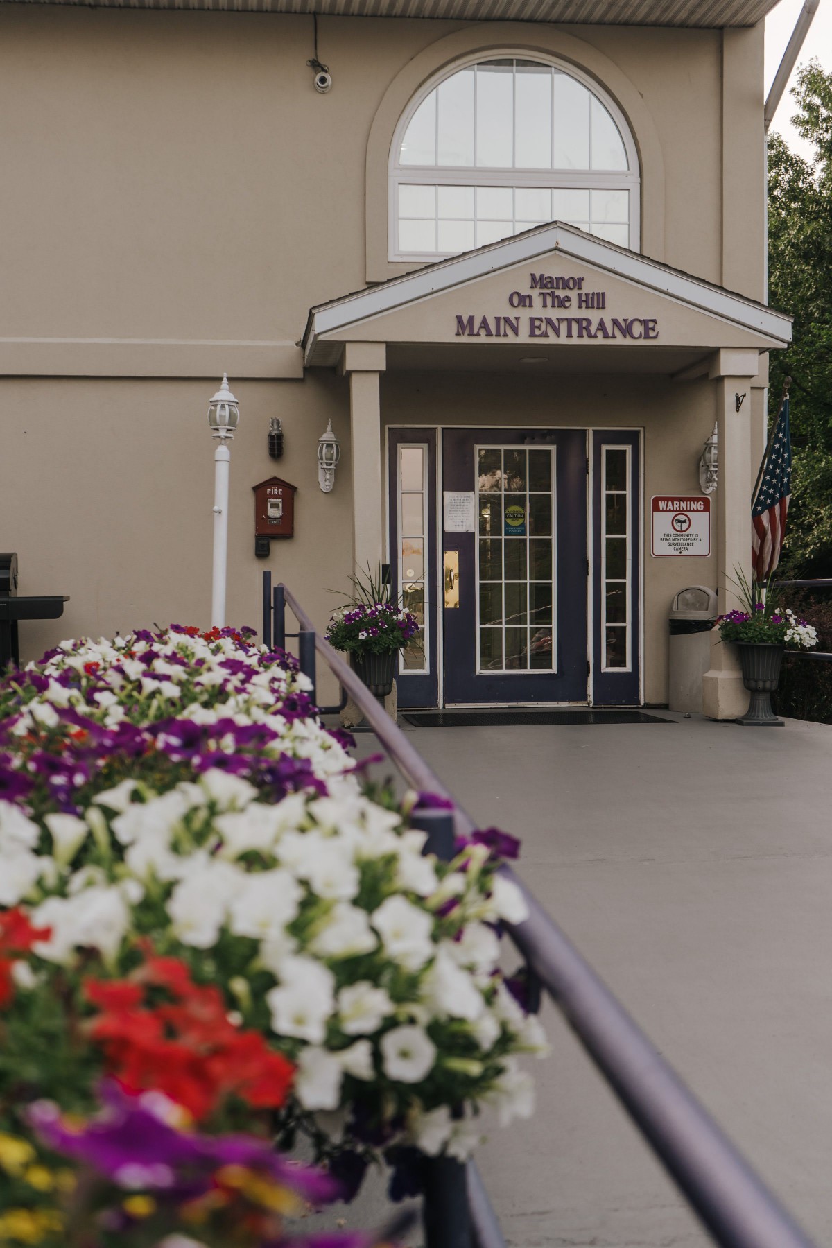 A welcoming entrance adorned with colorful flowers leading to a building's main doorway.
