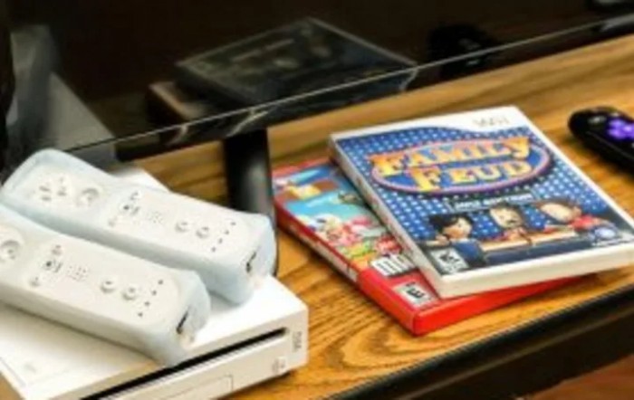 A set of Wii gaming controllers and game cases on a wooden table.