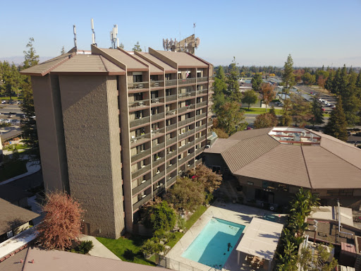 Aerial view of a hotel with a pool area surrounded by lush landscaping.