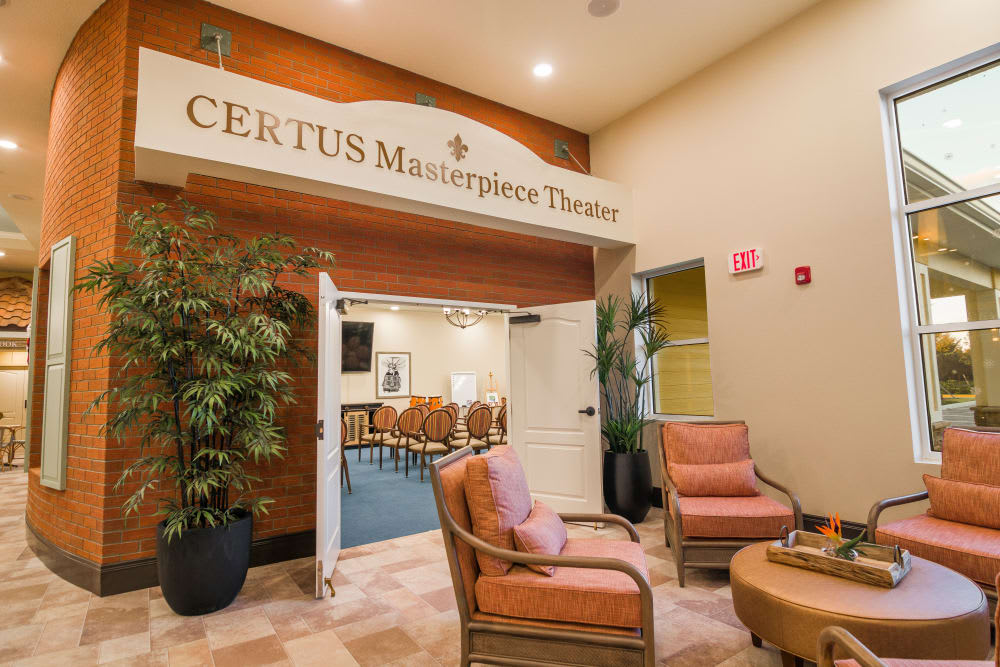 A cozy interior space leading to the CERTUS Masterpiece Theater, featuring comfortable lounge chairs and decorative plants.