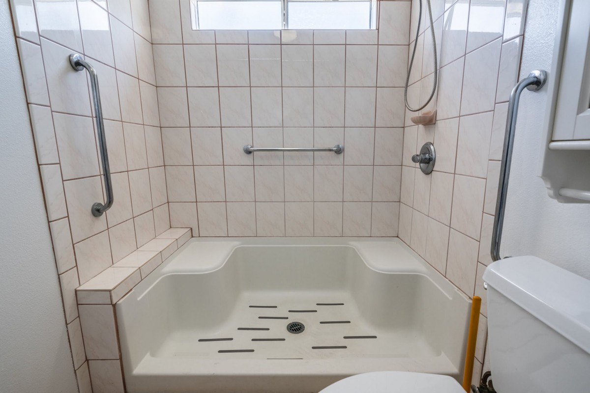 A tiled bathroom with a bathtub and shower setup.