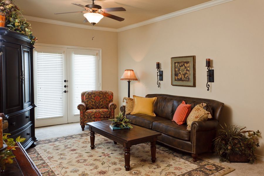 A cozy living room with a brown leather sofa, patterned armchair, and stylish decor.