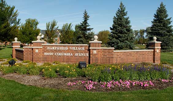 Entrance to Parkside Village with a landscaped sign surrounded by flowers and trees.