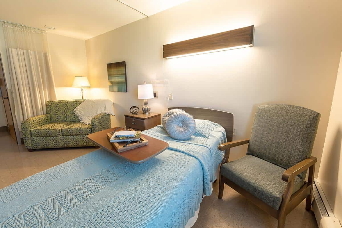 Cozy hospital room with a bed, side table, and seating area.