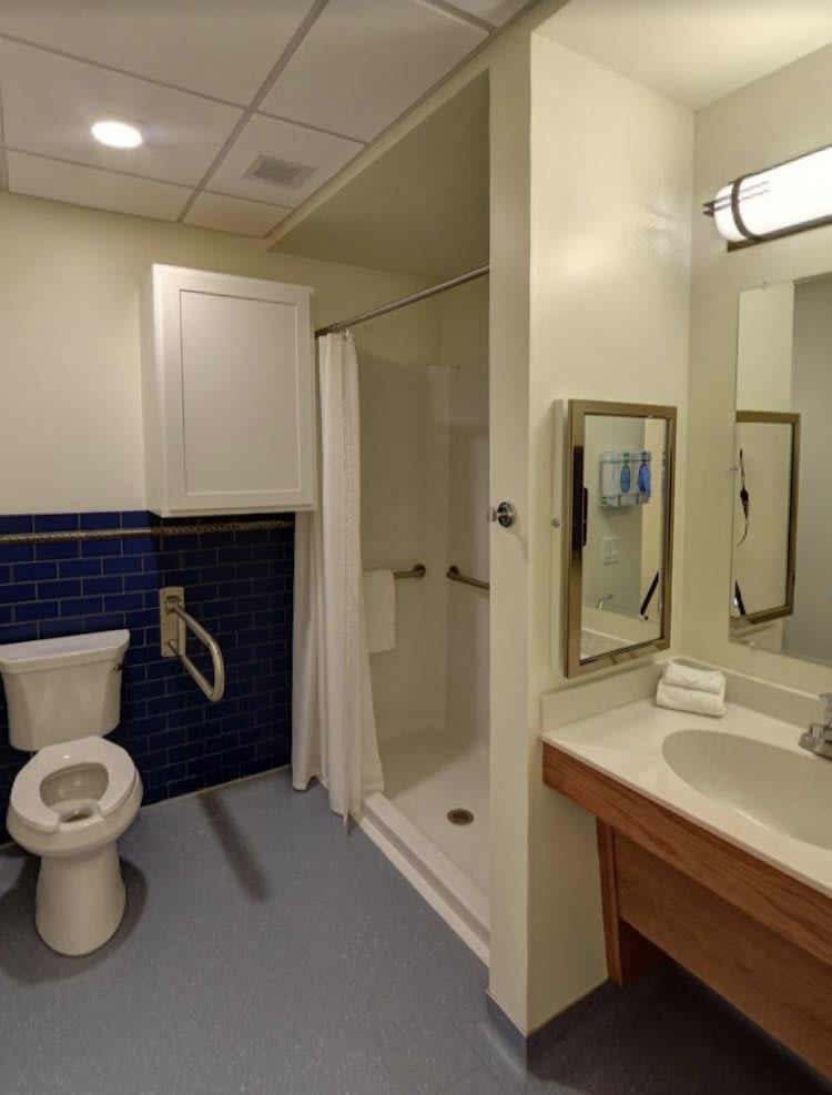 A clean and organized bathroom featuring a toilet, sink, shower, and mirror.