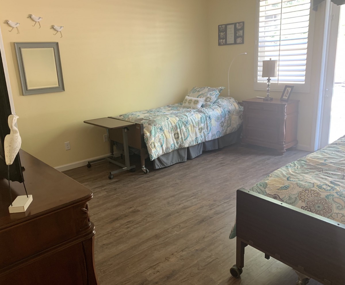 A simple bedroom with a single bed, wooden flooring, and minimal furniture.