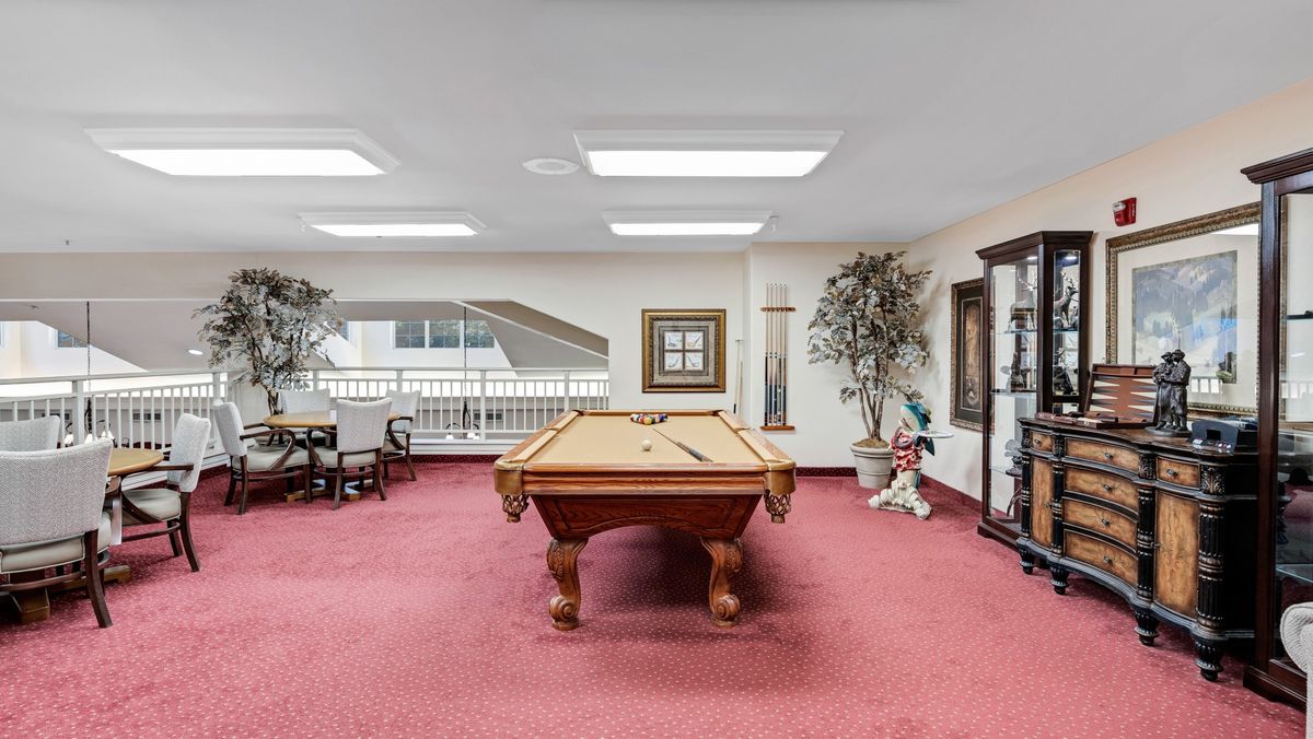 A spacious indoor billiard room featuring a pool table, chairs, and decorative elements.