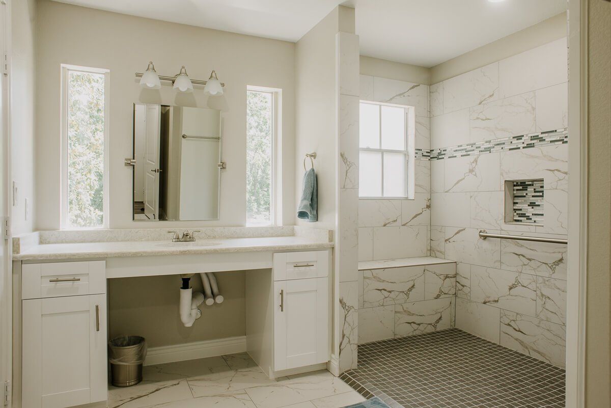 A modern bathroom with a marble-accented shower and a vanity area.