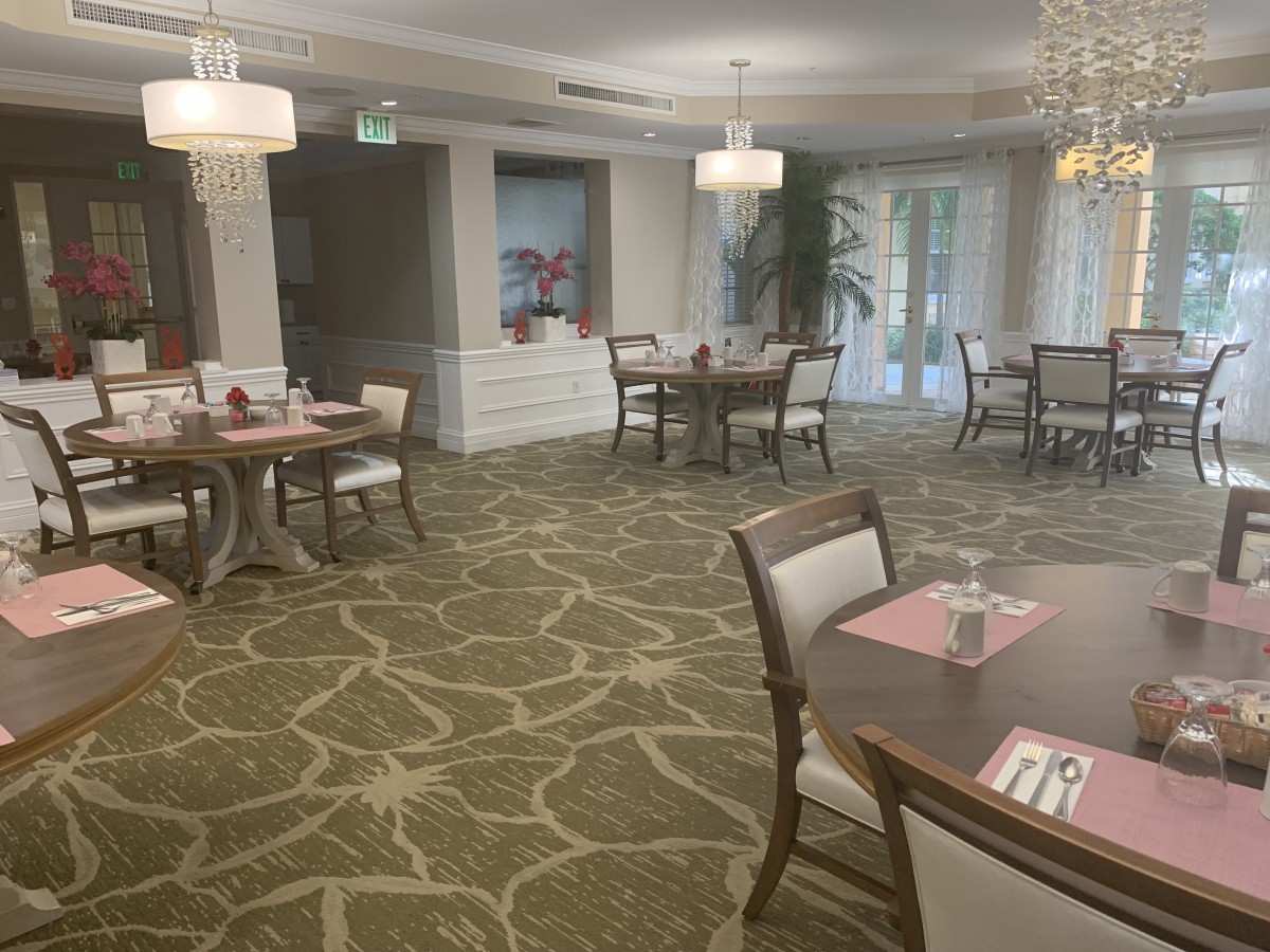 An elegant restaurant dining area with round tables and cushioned chairs, featuring tasteful decor and soft lighting.