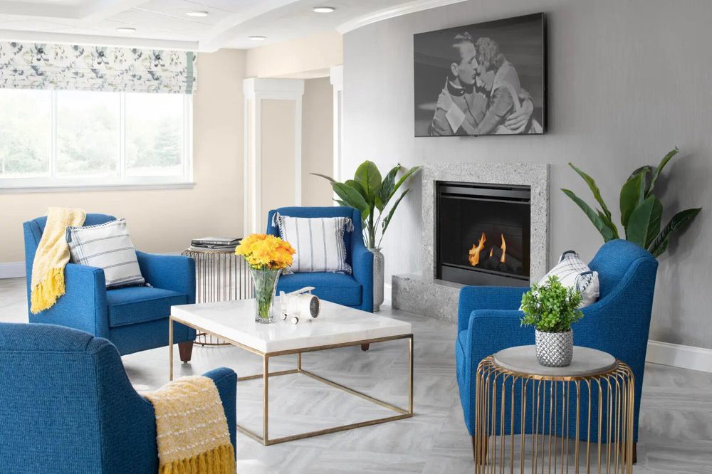 A modern living room with blue chairs, a fireplace, and stylish decor.