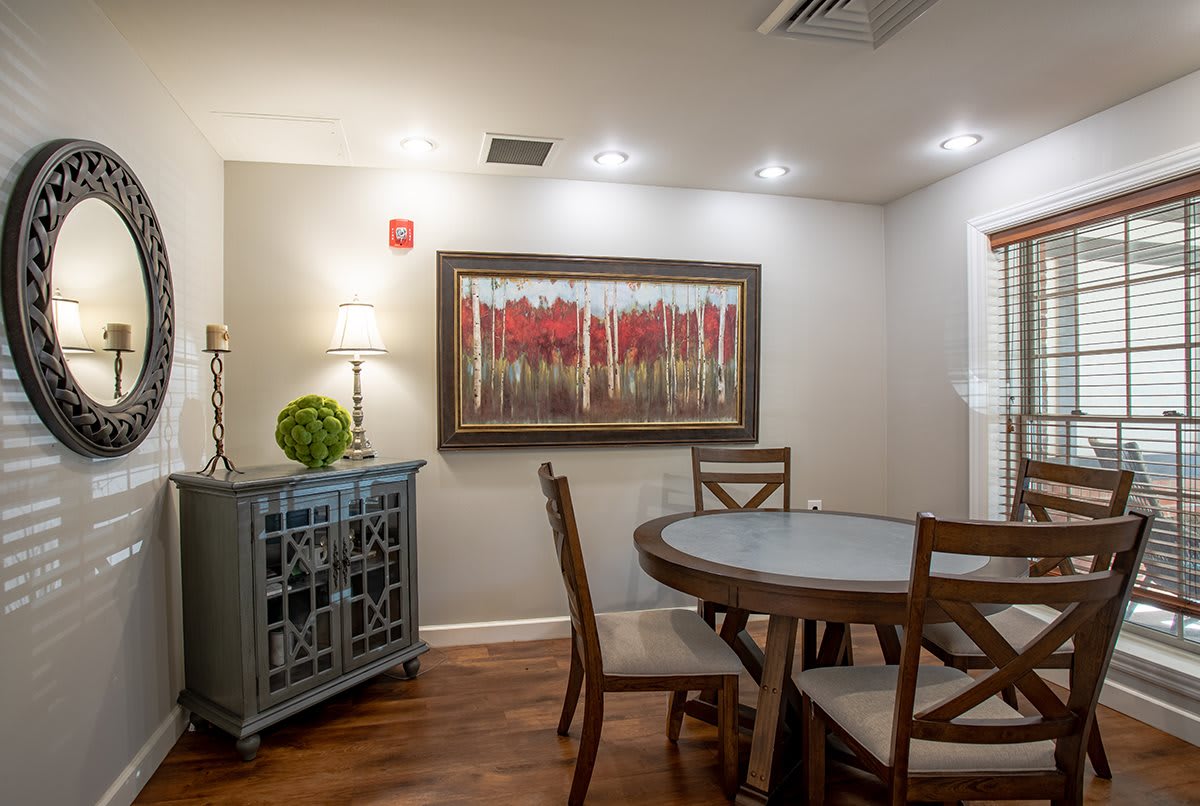 Cozy dining room with a round table, surrounded by wooden chairs and adorned with artwork on the wall.