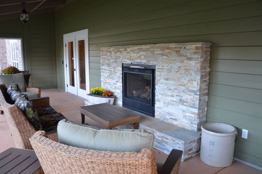 A cozy outdoor patio with a stone fireplace and comfortable seating.