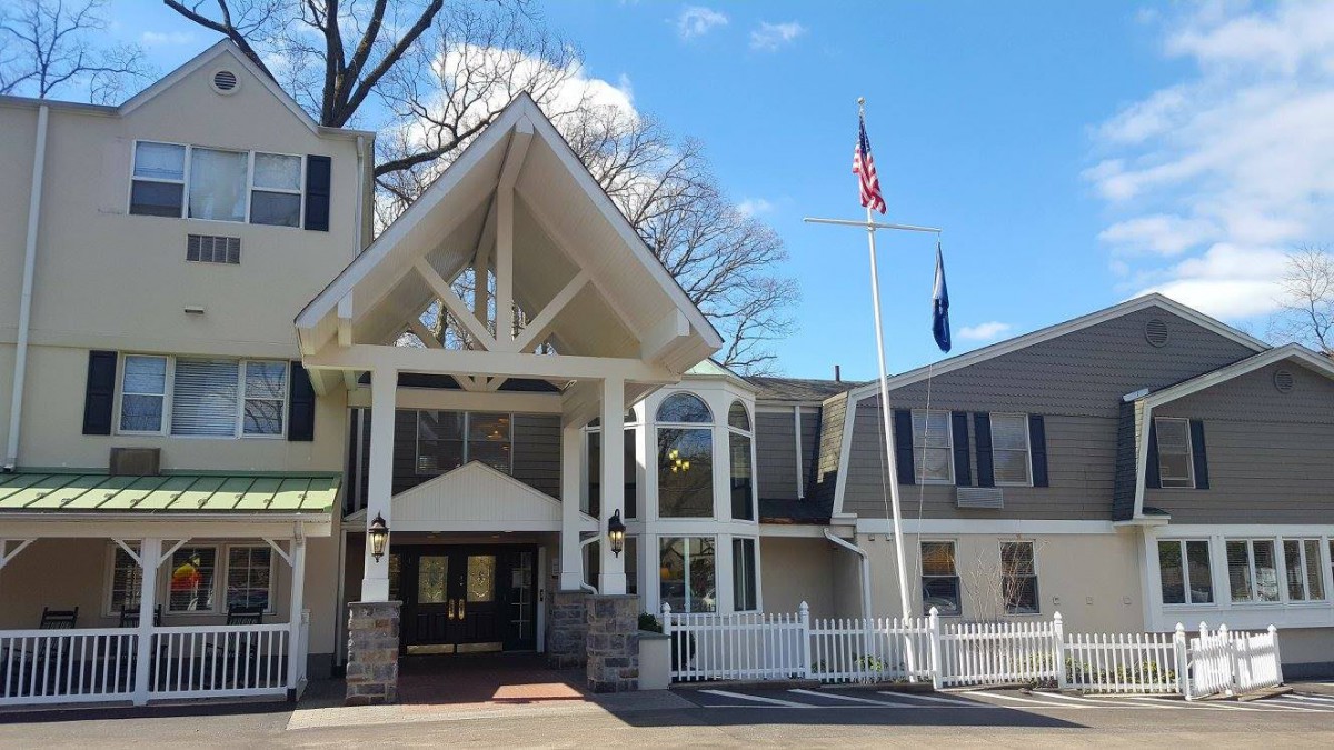 A view of a building entrance with flags and a clear blue sky.
