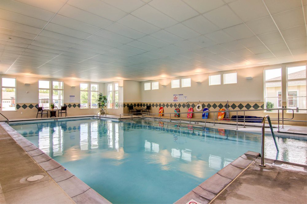 An indoor swimming pool with tiled floors and chairs along the side.