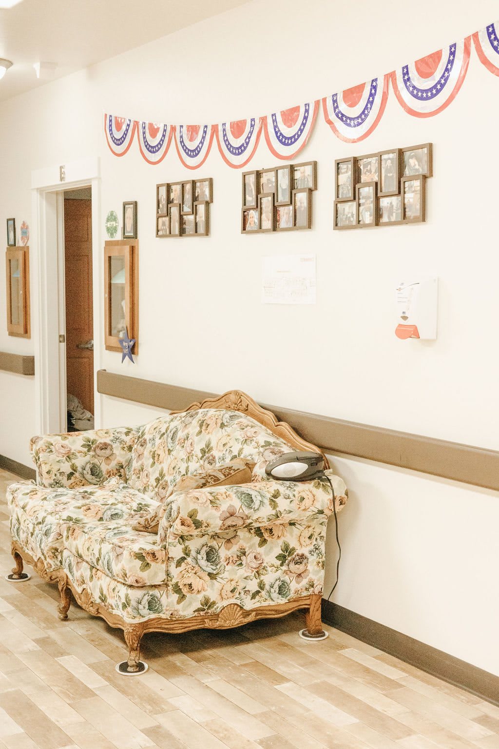 A cozy waiting area in a hallway featuring a floral-patterned sofa and wall decorations.