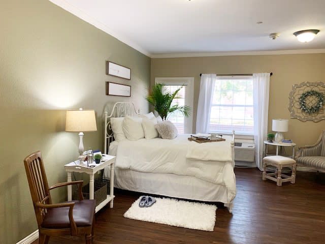 A cozy bedroom featuring a comfortable bed, bedside tables with lamps, and a large window letting in natural light.