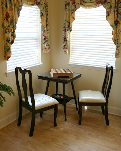 A quaint dining nook featuring a small table and two chairs, adorned with elegant window curtains.