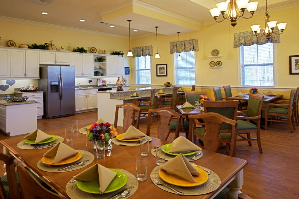 A brightly lit dining and kitchen area with a neatly arranged table setting.