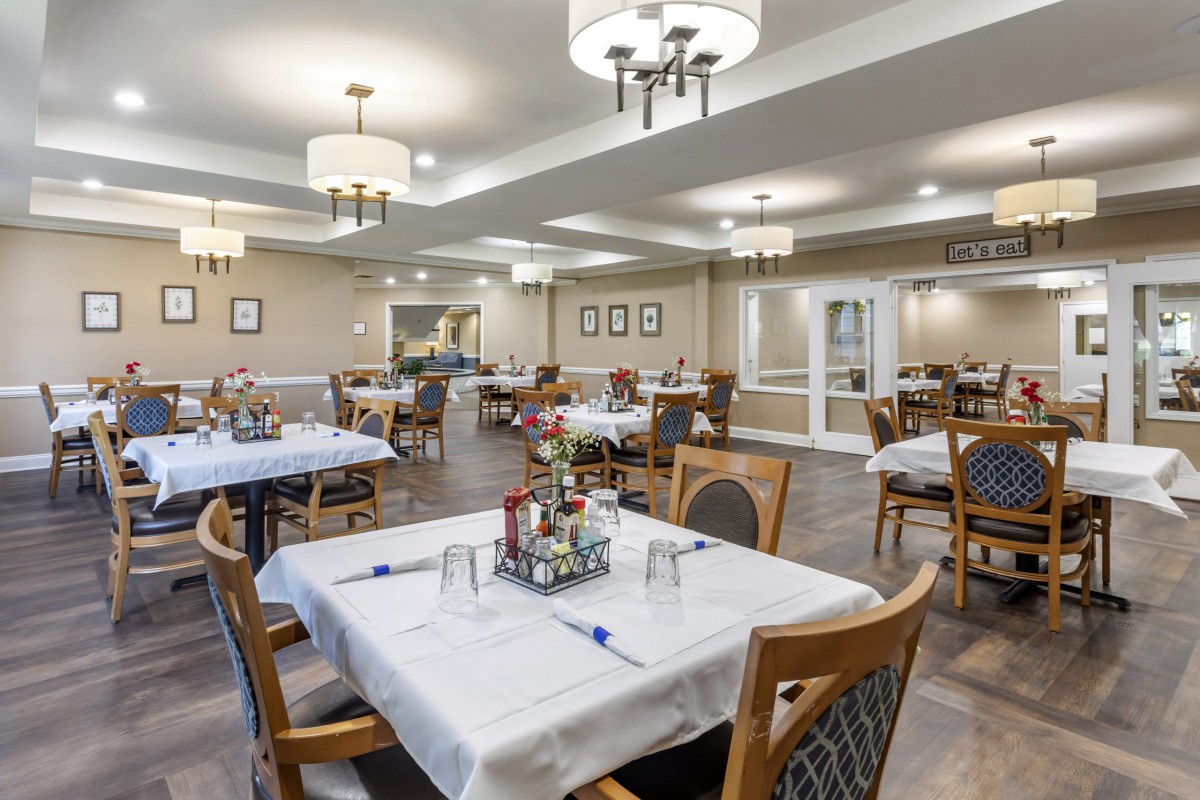 A well-lit dining area featuring neatly arranged tables and chairs with simple decor.