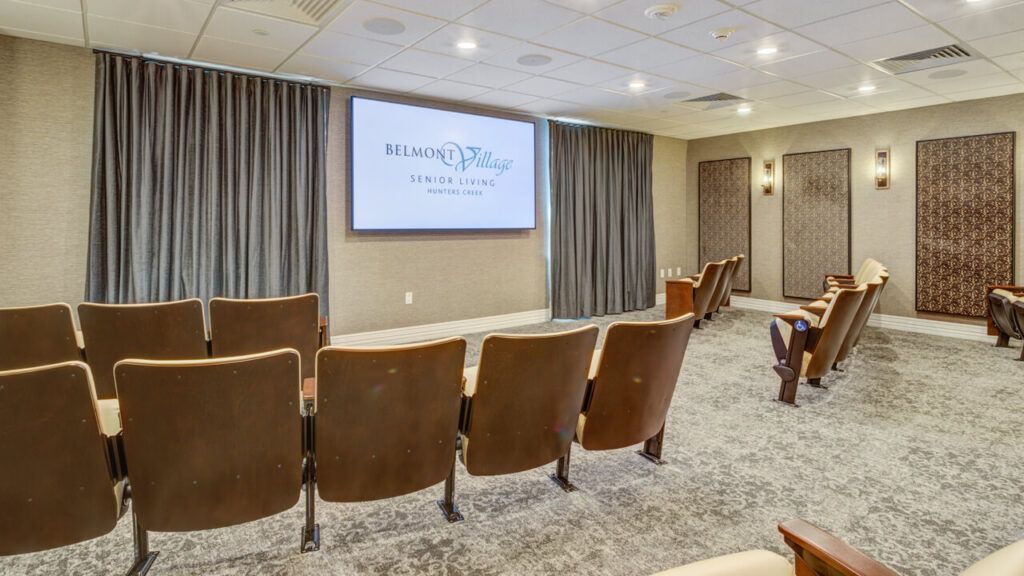 A small conference room with theater-style seating and a projector screen.