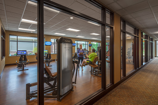 A view of a gym with various exercise equipment and individuals engaging in workouts.