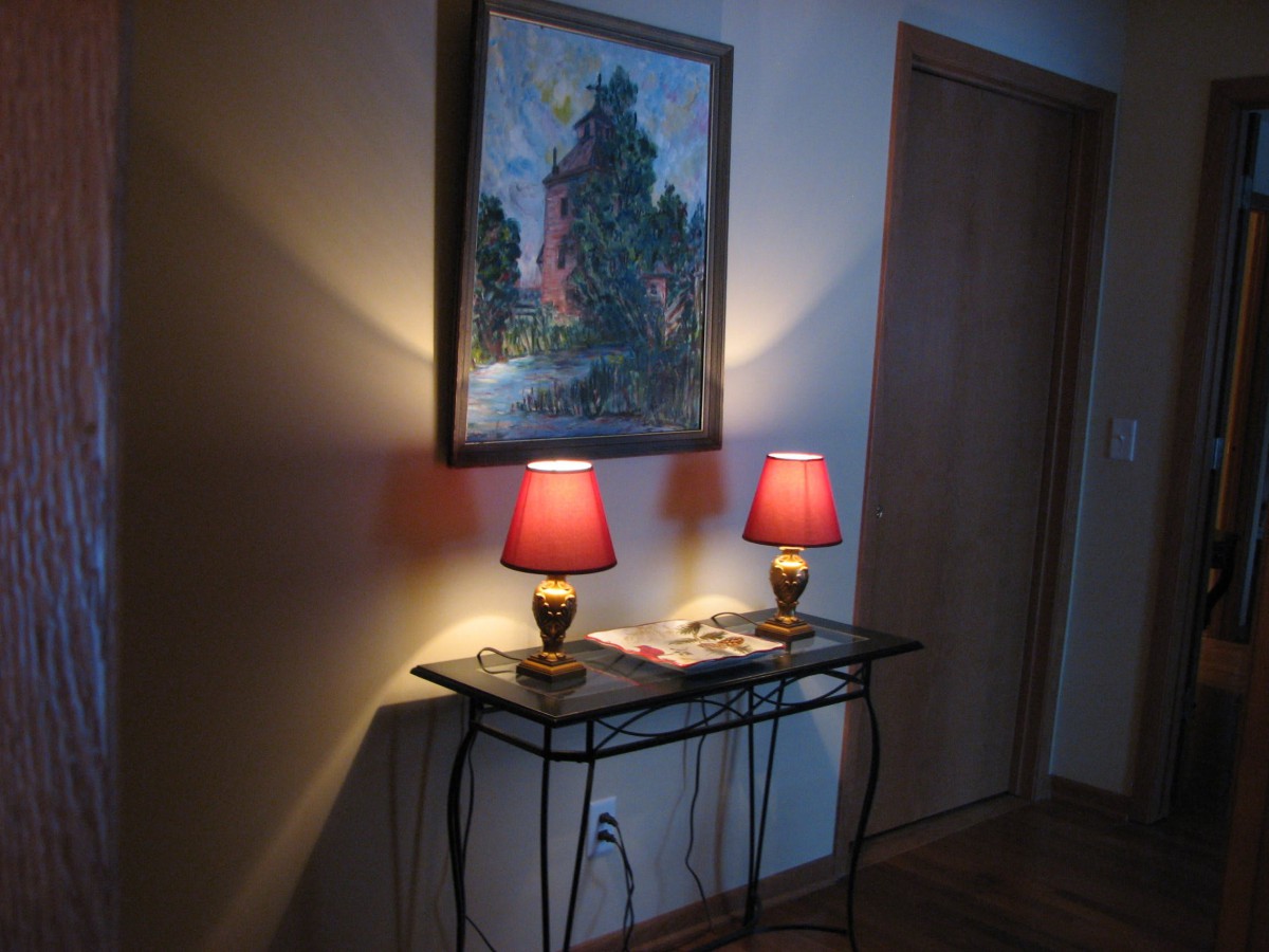 A cozy corner featuring two red lamps on a table beneath an impressionist-style painting.