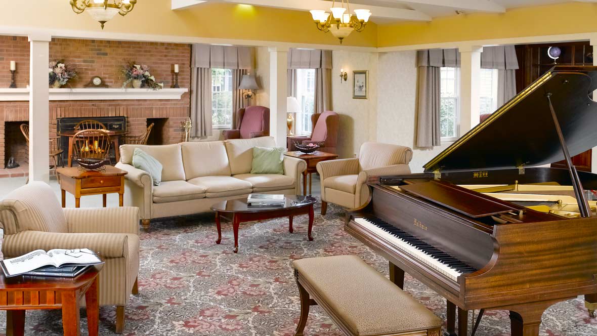 A cozy living room featuring a piano, comfortable seating, and a fireplace.