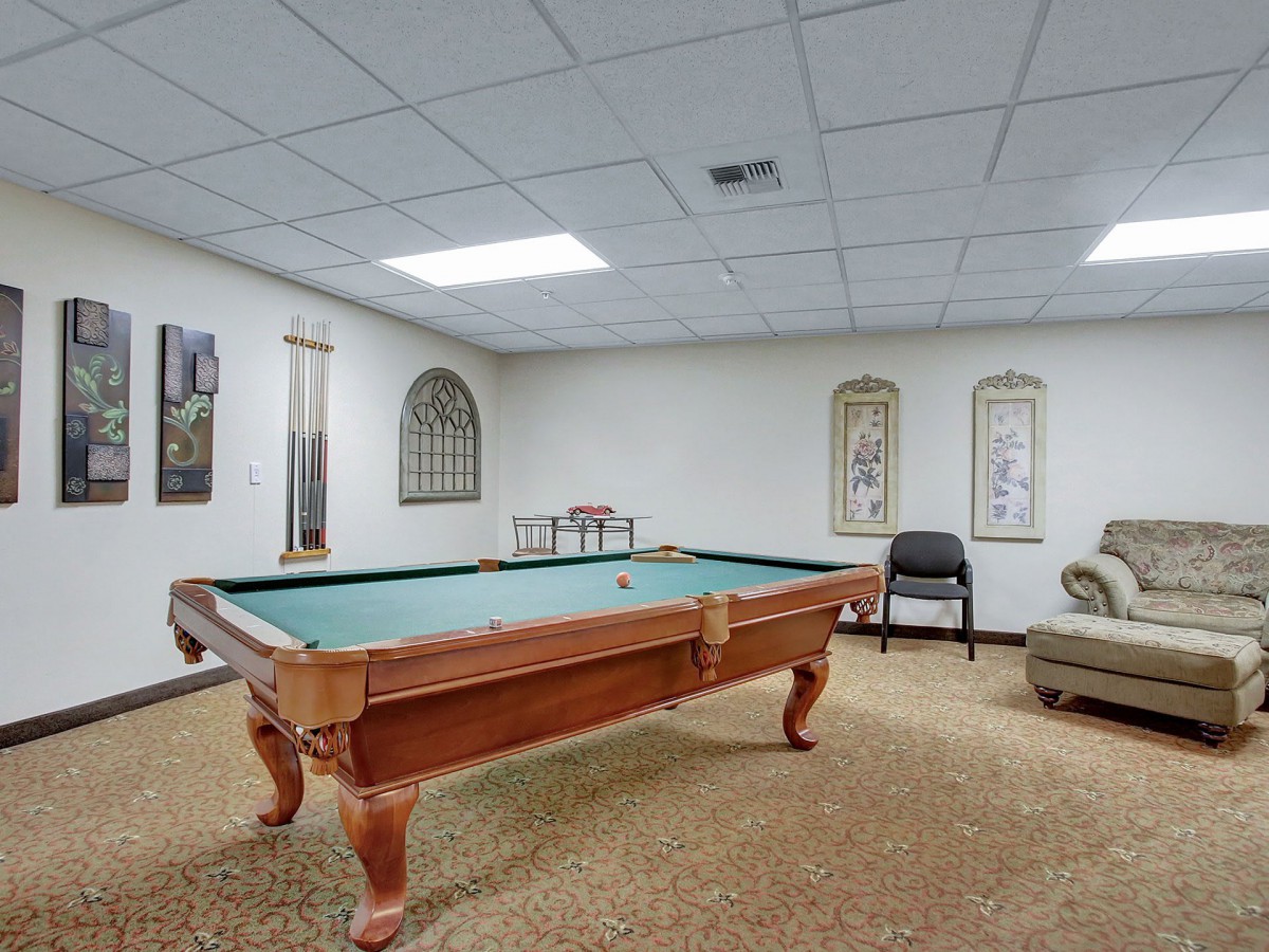A cozy game room featuring a pool table, comfortable seating, and decorative wall art.