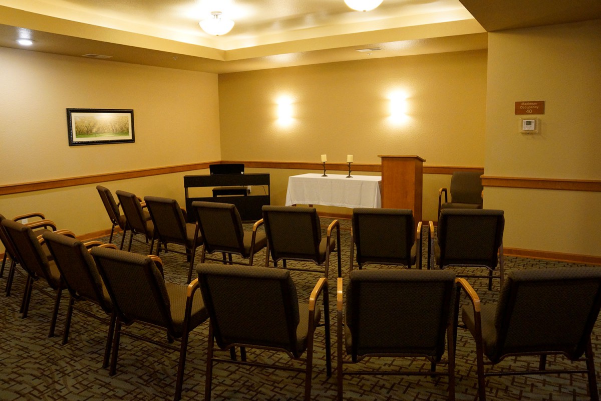 An empty meeting room set up with chairs facing a podium and table with candles.