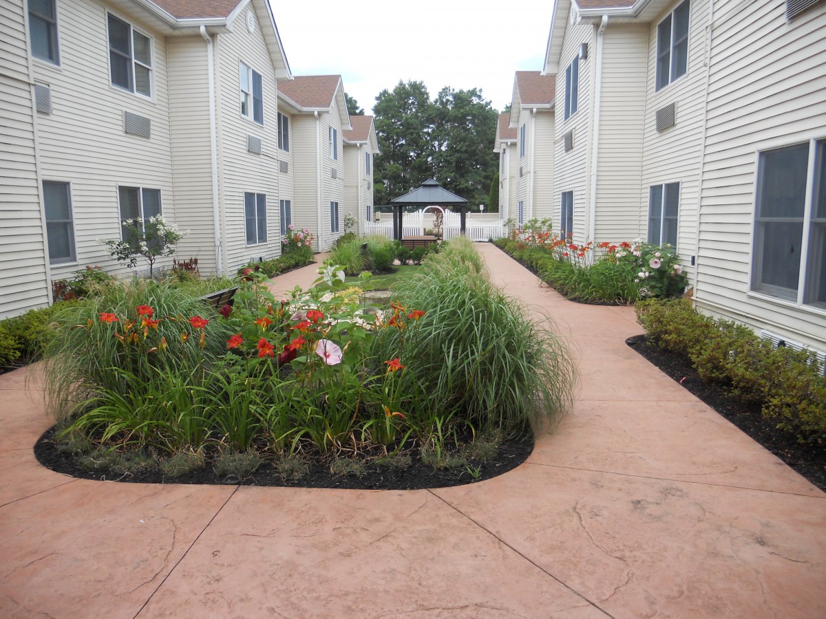 A well-maintained apartment complex with a landscaped pathway and a gazebo in the center.