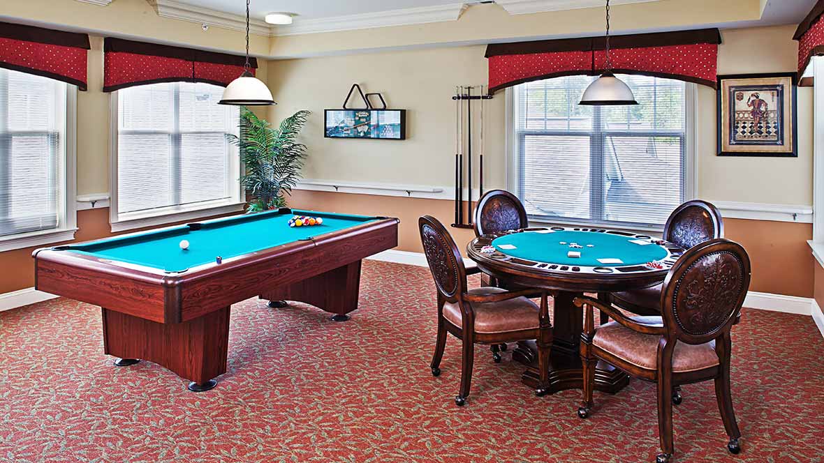 A cozy gaming room featuring a pool table and a card table with chairs, designed for leisure and relaxation.