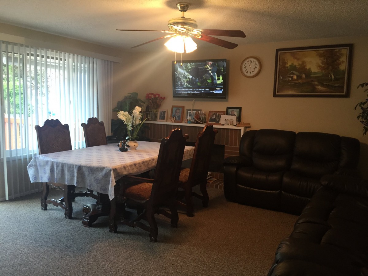 A cozy living and dining space featuring a table with chairs, a sofa, and a television mounted on the wall.