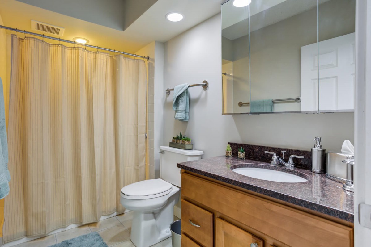 A well-lit bathroom with a shower curtain, vanity, and mirror.