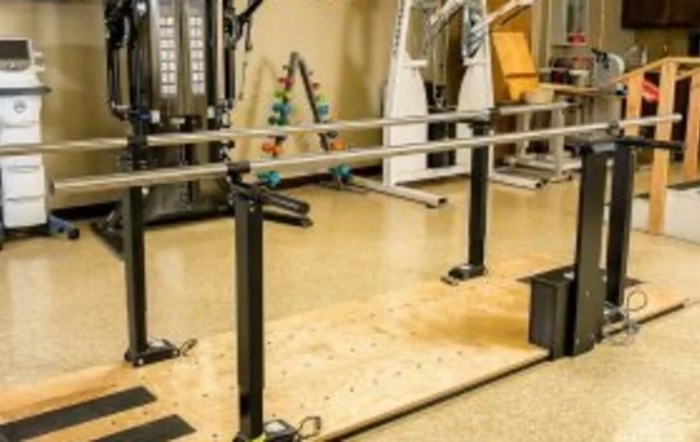 A rehabilitation area featuring parallel bars and gym equipment.
